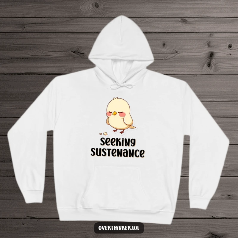 Funny hoodie illustrating a bird character nervously pecking at a solitary, unmoving crumb, representing anxiety and focused attention.