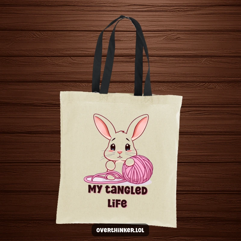 Funny tote bag with a bewildered rabbit contemplating a tangled yarn ball, perfect for carrying craft supplies.